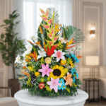 Arreglo floral tropical con girasoles, lirios, aves del paraíso y follaje verde sobre un pedestal blanco en una sala elegante