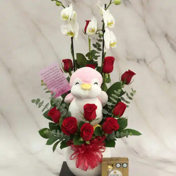 Arreglo Floral ALICE: Orquídea, Rosas Rojas y Peluche para Regalo Arreglo floral ALICE con orquídeas blancas, rosas rojas frescas, peluche de pingüino rosa y chocolates Ferrero Rocher, ideal