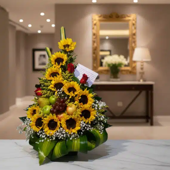 Arreglo Floral Dorado: Girasoles, Rosas y Frutas Frescas para Regalar Arreglo floral dorado con girasoles, rosas rojas, uvas, manzanas y peras verdes, sobre una mesa de mármol en un elegante reci