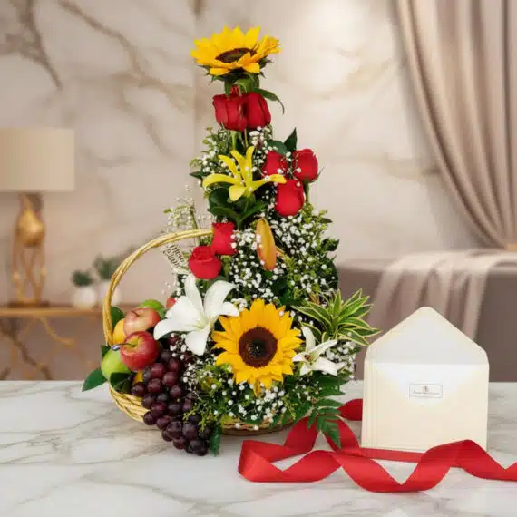 Arreglo floral Capella con girasoles, rosas rojas, lirios blancos y frutas frescas en una canasta, con tarjeta de regalo y ci