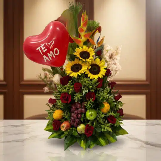 Arreglo floral premium con girasoles, rosas rojas, frutas tropicales (uvas, manzanas, naranjas) y un globo rojo de corazón co