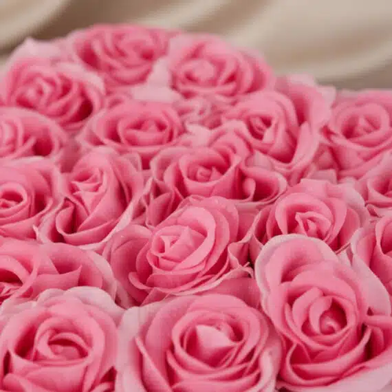 Primer plano extremo de un arreglo floral de rosas rosadas en forma de corazón, con gotas de rocío sutiles y textura hiperrea