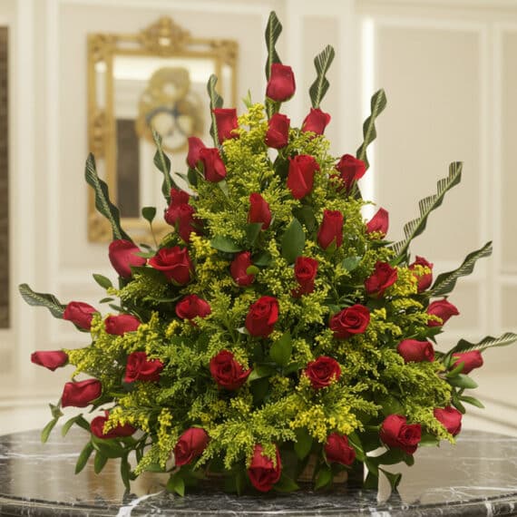 Arreglo floral premium con rosas rojas Cupido y follaje verde, sobre una mesa de mármol en un lobby de hotel boutique, ideal