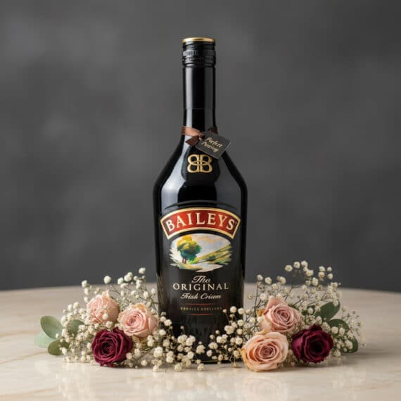 Botella de Baileys 700ml con Arreglo Floral Elegante para Regalo Botella de Baileys The Original Irish Cream de 700ml, rodeada por un delicado arreglo floral de rosas rosadas y burdeos, y fl