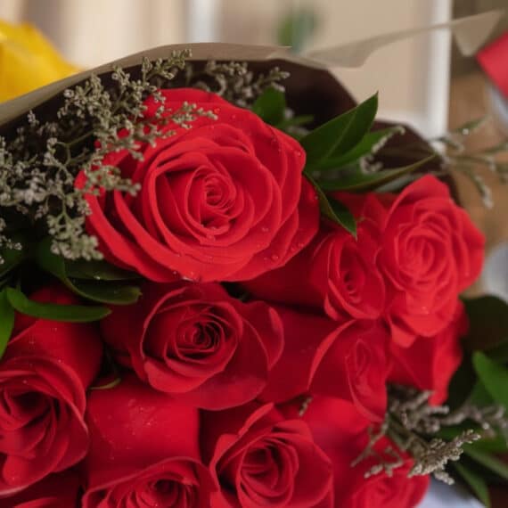 Primer plano extremo de un bouquet de rosas rojas frescas con gotas de rocío, textura hiperrealista y colores vibrantes bajo