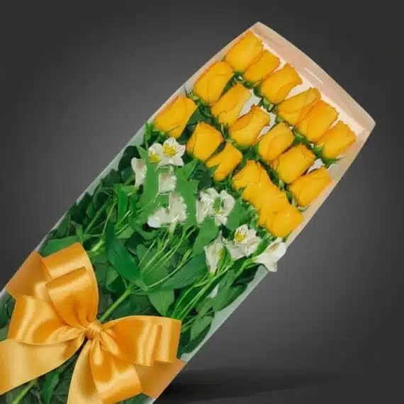 Caja de 18 rosas amarillas frescas con follaje verde y lazos dorados, ideal para regalar en cualquier ocasión especial.