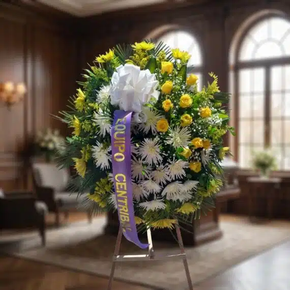 Corona Fúnebre Estamos Contigo: Elegancia y Respeto en Momentos Difíciles Corona fúnebre 'Estamos Contigo' con flores amarillas y blancas, lazo morado, en sala de velación premium con luz natural sua