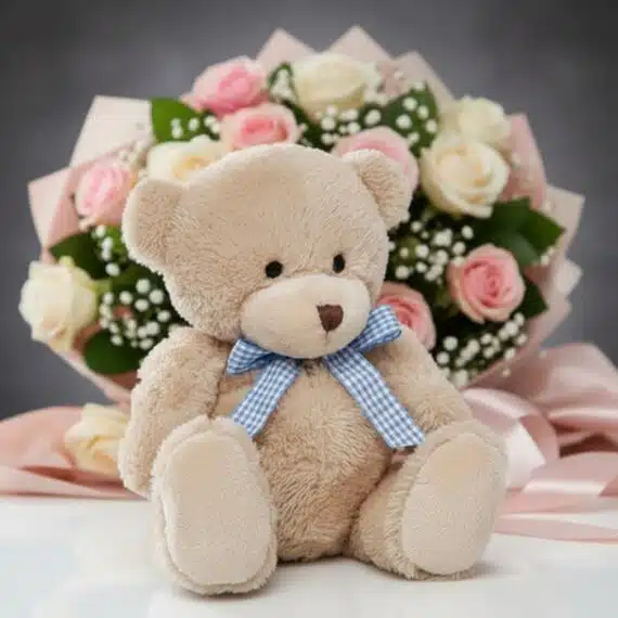 Oso de felpa color miel con lazo azul a cuadros, sentado frente a un elegante ramo de rosas rosadas y blancas, ideal para reg